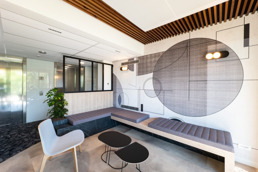 Auxiliaire BTP espace detente informel tisanerie avec mur decoratif banquette confortable et chaise design